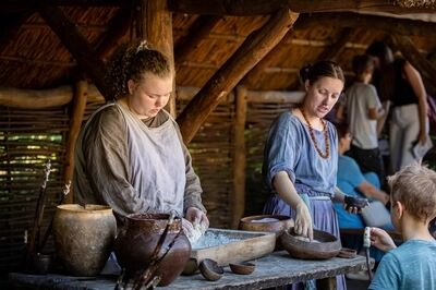 Historische bewoner kneedt brood in Museumpark VONK (voormalig preHistorisch Dorp)