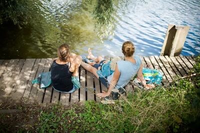 Twee vrouwen zitten op vlonder aan het water