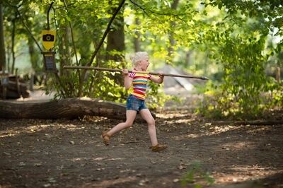 Meisje werpt speer in het bos