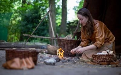 Historische bewoner maakt vuur voor haar tent